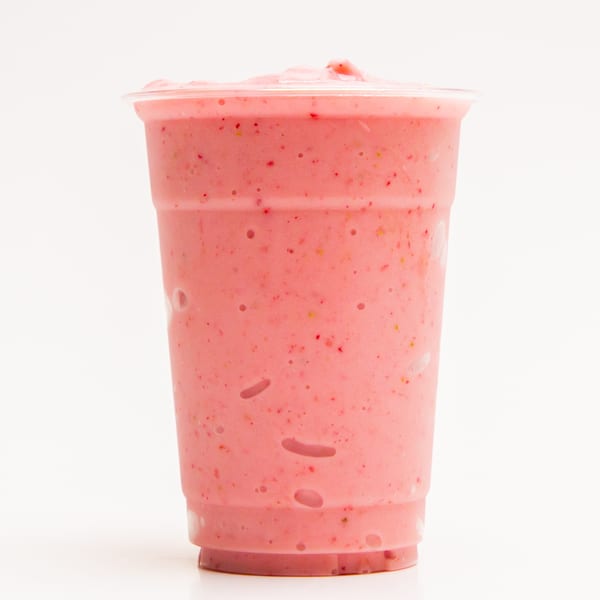 A Superfood Cafe strawberry smoothie in a clear plastic cup on a white background.