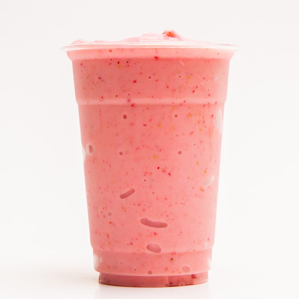 A Superfood Cafe strawberry smoothie in a clear plastic cup on a white background.