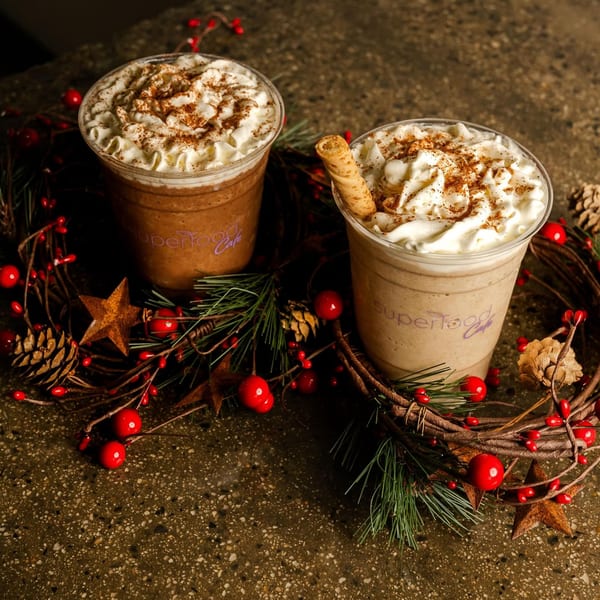 Two Superfood Cafe smoothies with whipped cream and cinnamon, surrounded by a festive wreath.