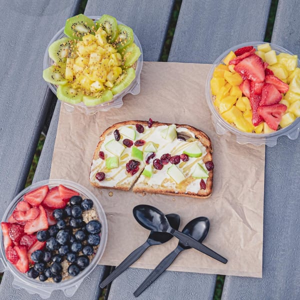 Overhead view of Superfood Cafe's fruit bowls and avocado toast on a gray picnic table.