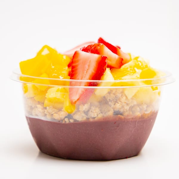 Superfood Cafe's acai bowl with granola, mango, and strawberries in a clear plastic cup.