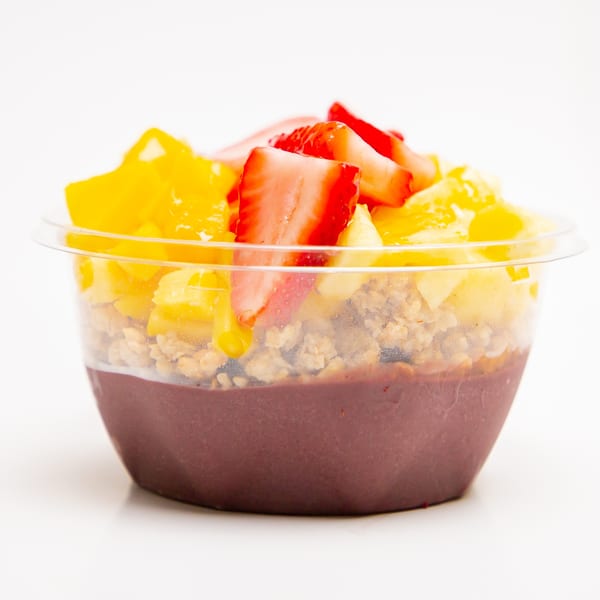 Superfood Cafe's acai bowl with granola, mango, and strawberries in a clear plastic cup.