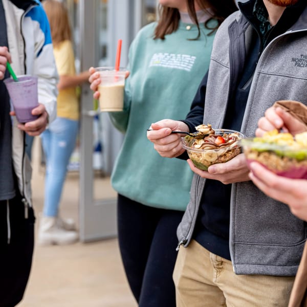 Customers at Superfood Cafe enjoying healthy acai bowls and smoothies with colorful toppings.