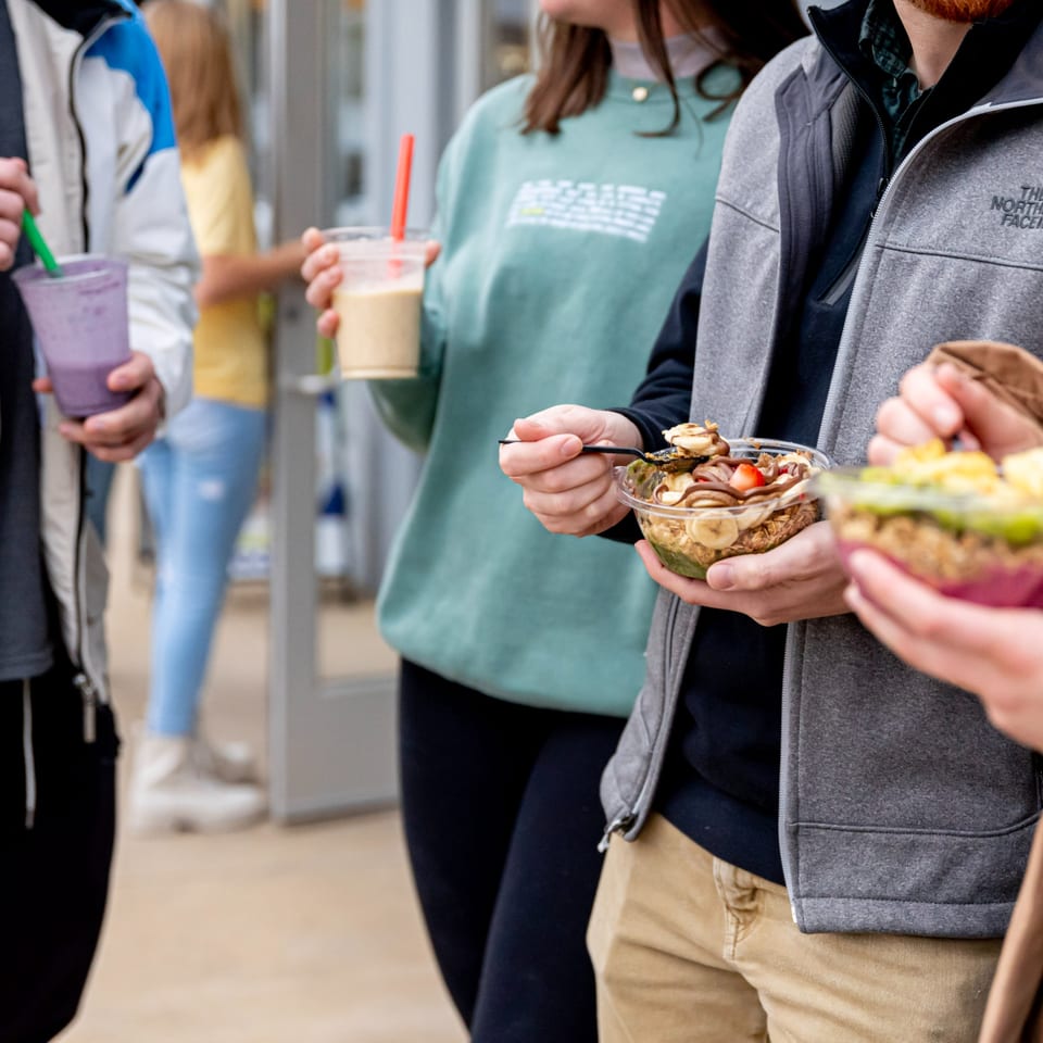 Customers at Superfood Cafe enjoying healthy acai bowls and smoothies with colorful toppings.
