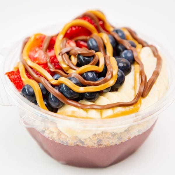 A Superfood Cafe acai bowl with strawberries, blueberries, bananas, peanut butter, and chocolate drizzle.