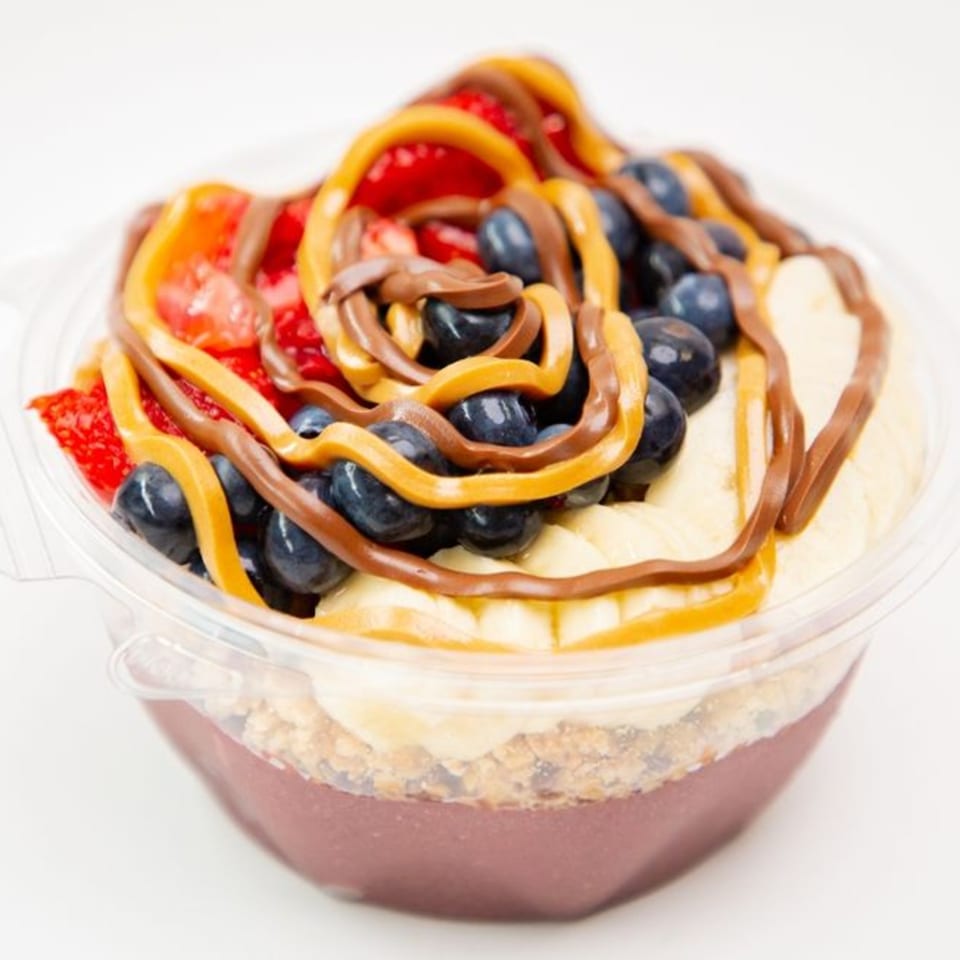 A Superfood Cafe acai bowl with strawberries, blueberries, bananas, peanut butter, and chocolate drizzle.